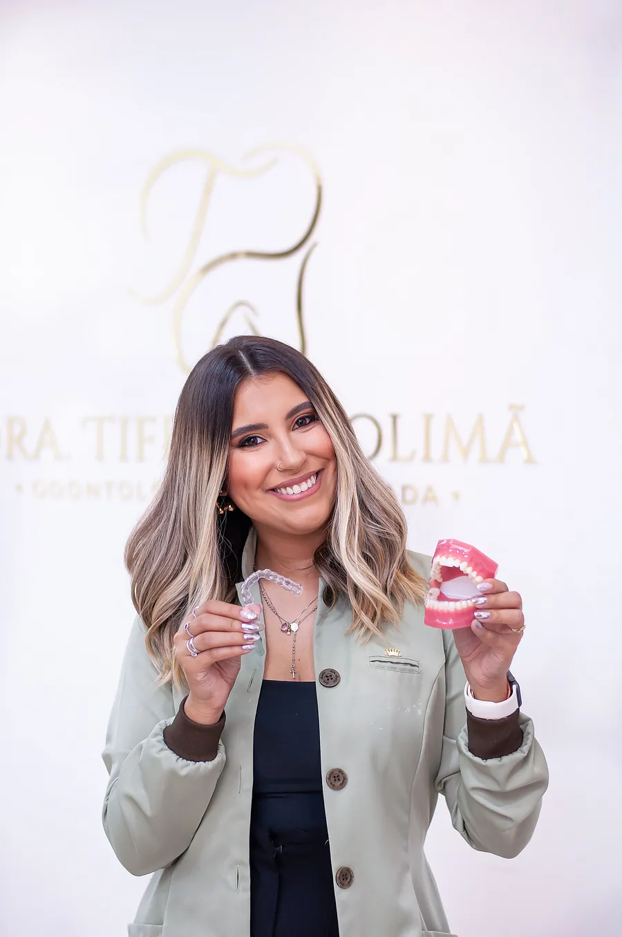 Dra. Tiffany mostrando um modelo com aparelho fixo e um alinhador