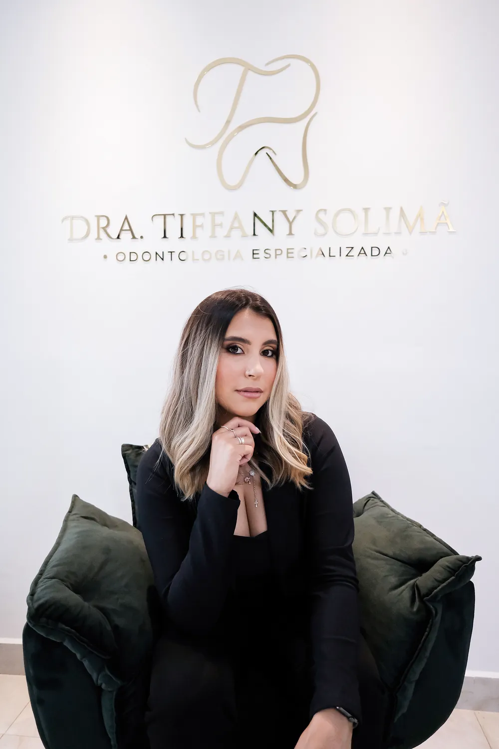 Dra. Tiffany Solimã na recepção do consultório, em frente ao logotipo Odontologia Especializada