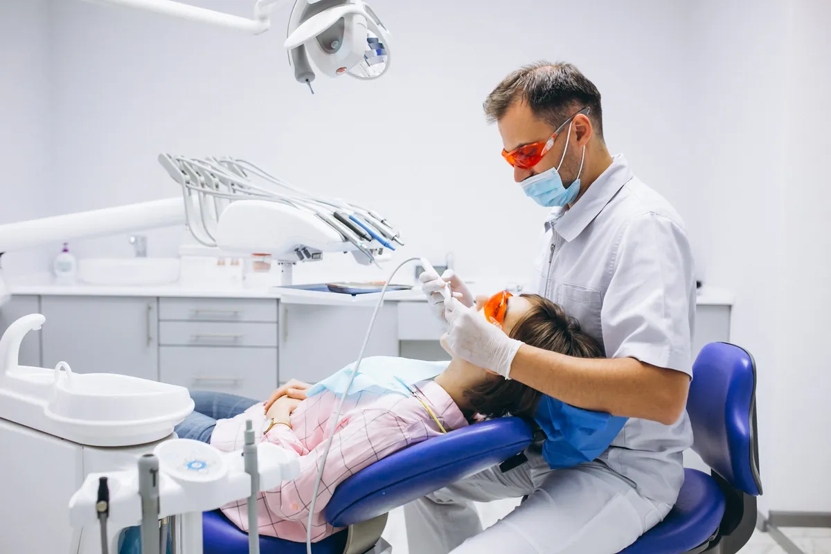 Dentista realizando tratamento odontológico em paciente